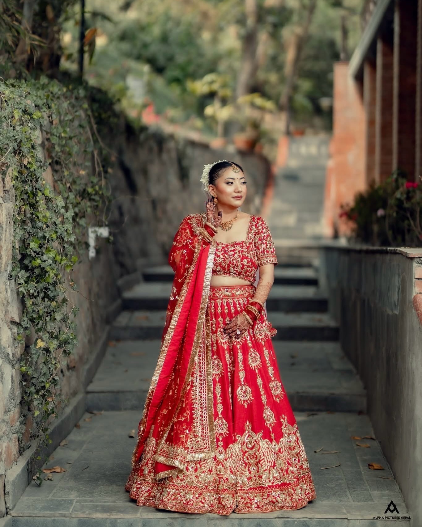 Kusum in a red embroidered lehenga on a set of stone steps