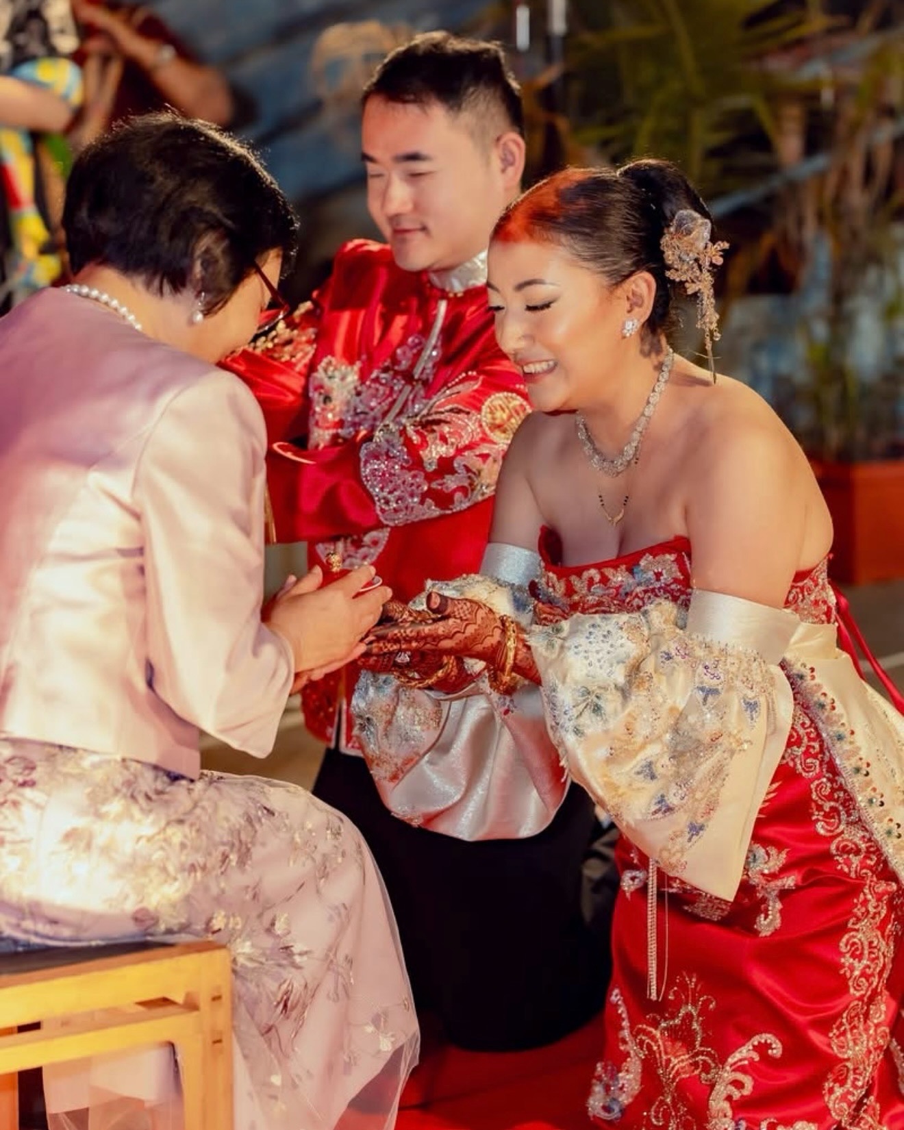 Kusum and her husband in red, an older guest holding Kusum’s hands