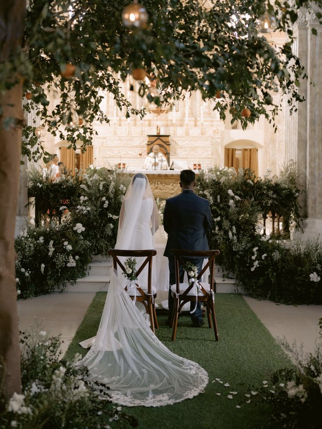 Shaibyaa and Eshan from behind at the altar of the church, under orange trees