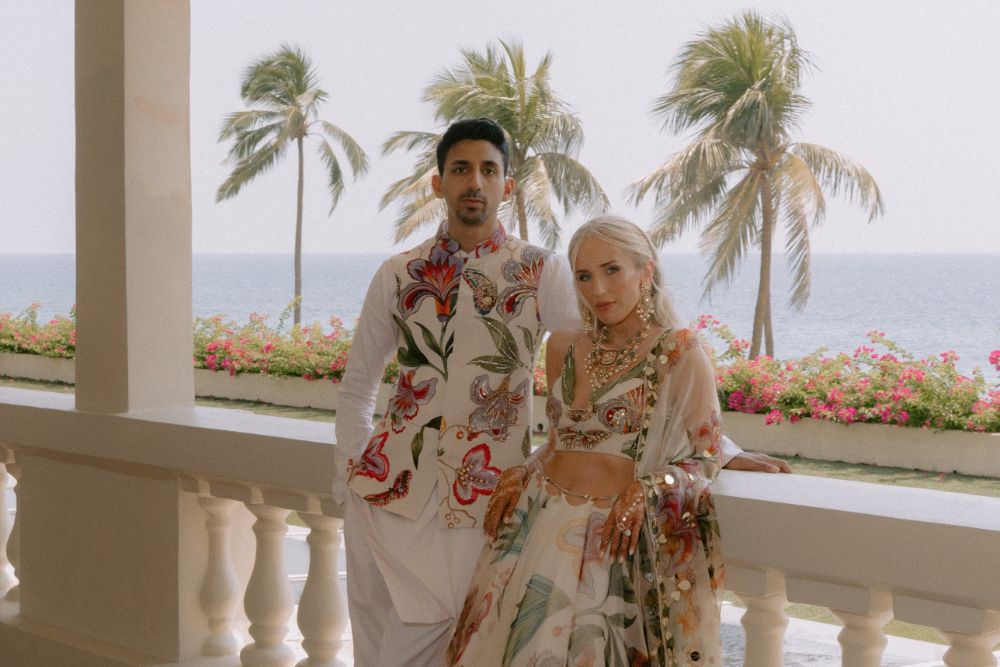 Natalia and Karan on a hotel balcony above the sea, among palm trees