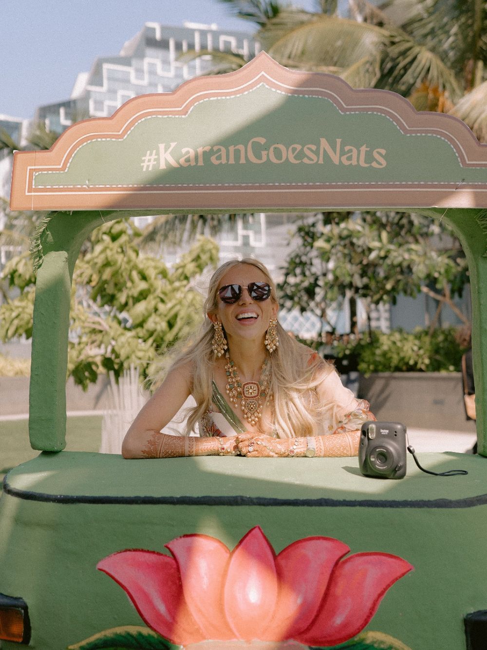 Natalia in sunglasses leaning out of a green rickshaw painted with a lotus