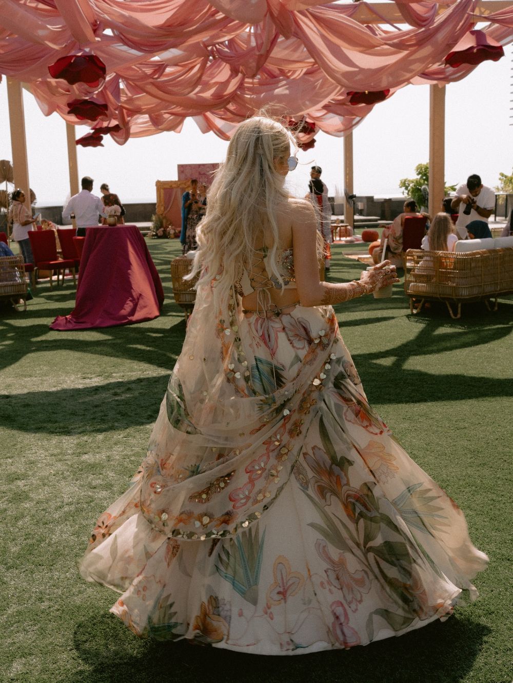 Natalia in a floral lehenga twirling across the lawn under peach drapes